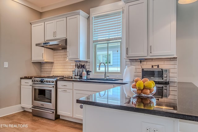 kitchen featuring sink, stainless steel gas stove, white cabinetry, and light wood-type flooring