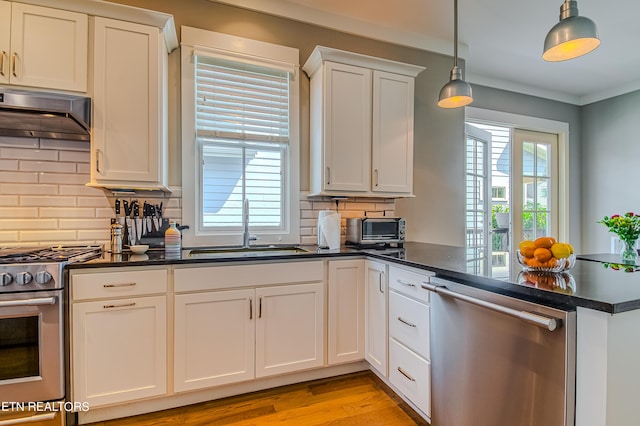 kitchen featuring stainless steel appliances, decorative backsplash, white cabinets, decorative light fixtures, and sink