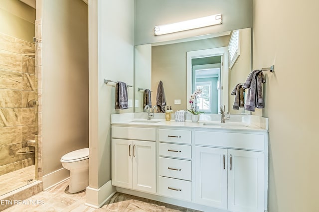 bathroom with toilet, vanity, and tiled shower