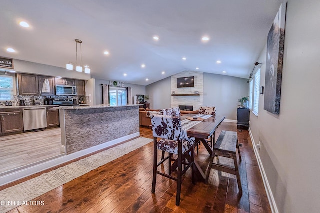 dining room featuring vaulted ceiling, a fireplace, and light wood-type flooring