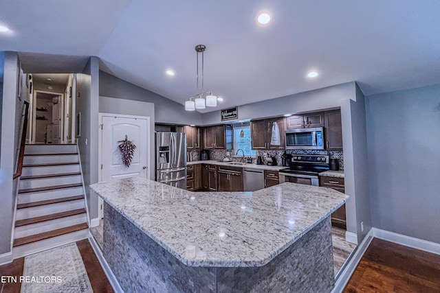 kitchen with appliances with stainless steel finishes, tasteful backsplash, sink, hanging light fixtures, and a large island