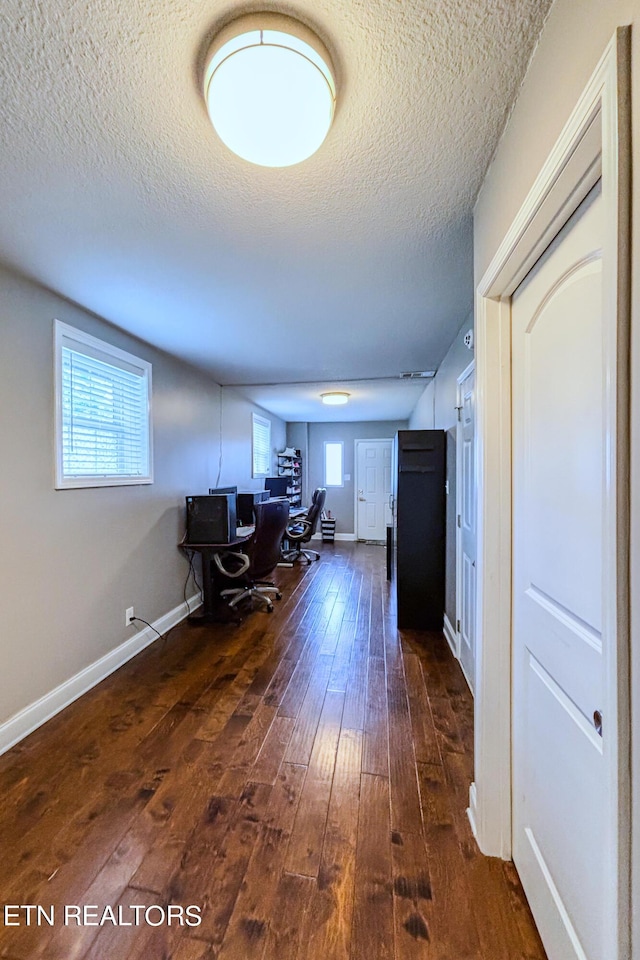 unfurnished office with a textured ceiling and dark hardwood / wood-style floors