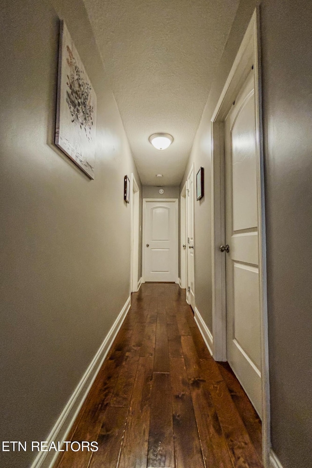 hall featuring a textured ceiling and dark hardwood / wood-style floors