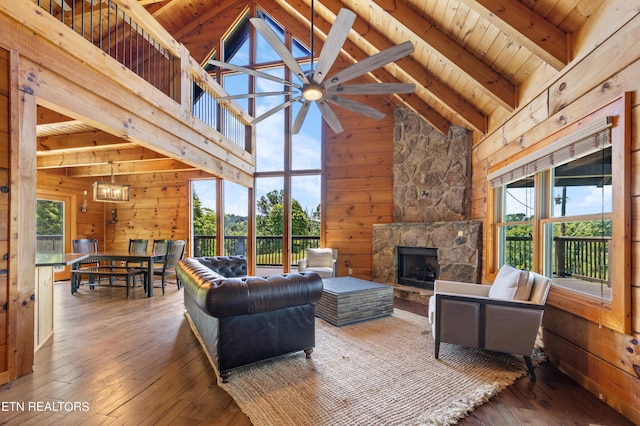 living room featuring beamed ceiling, plenty of natural light, a stone fireplace, and high vaulted ceiling