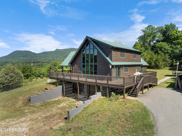 rear view of property featuring a deck with mountain view and a lawn