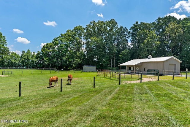 surrounding community with a rural view, an outbuilding, and a lawn