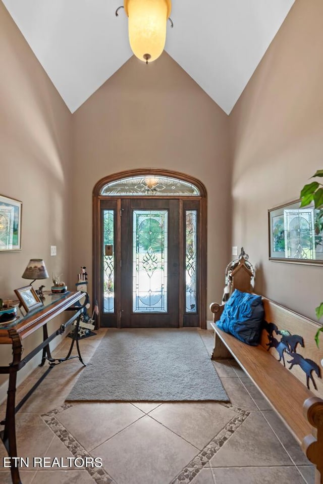 foyer with tile patterned flooring and high vaulted ceiling