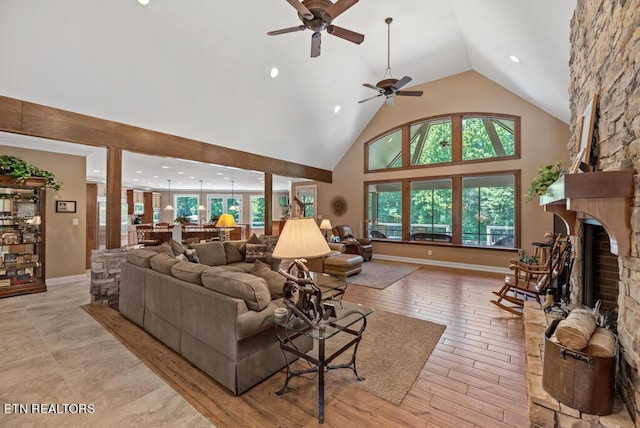 living room featuring ceiling fan, a fireplace, and a towering ceiling