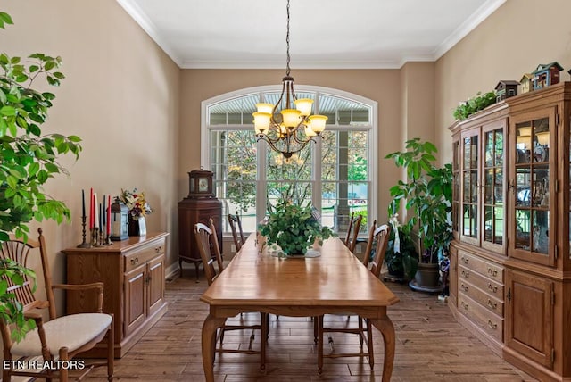 dining room featuring wood-type flooring, crown molding, and an inviting chandelier