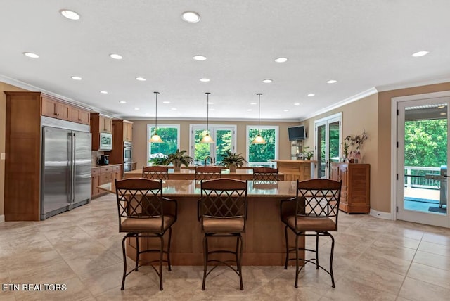 kitchen featuring crown molding, a breakfast bar, built in appliances, and pendant lighting