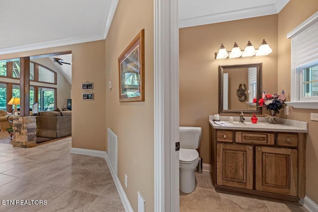 bathroom with ceiling fan, vanity, toilet, lofted ceiling, and crown molding