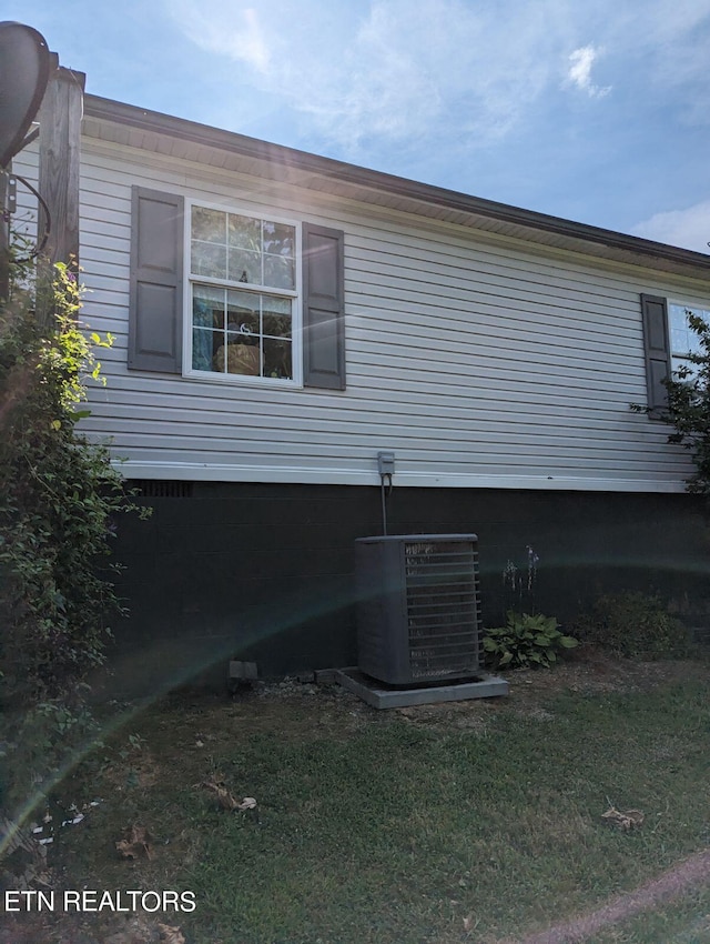 view of side of home with a lawn and cooling unit