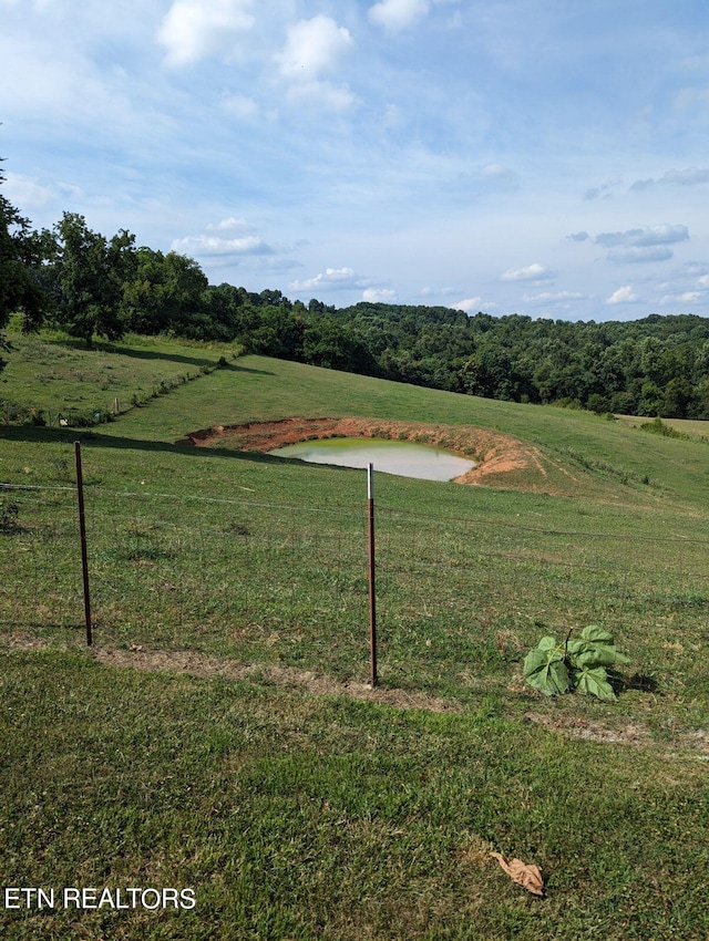 view of yard with a rural view, a water view, and fence