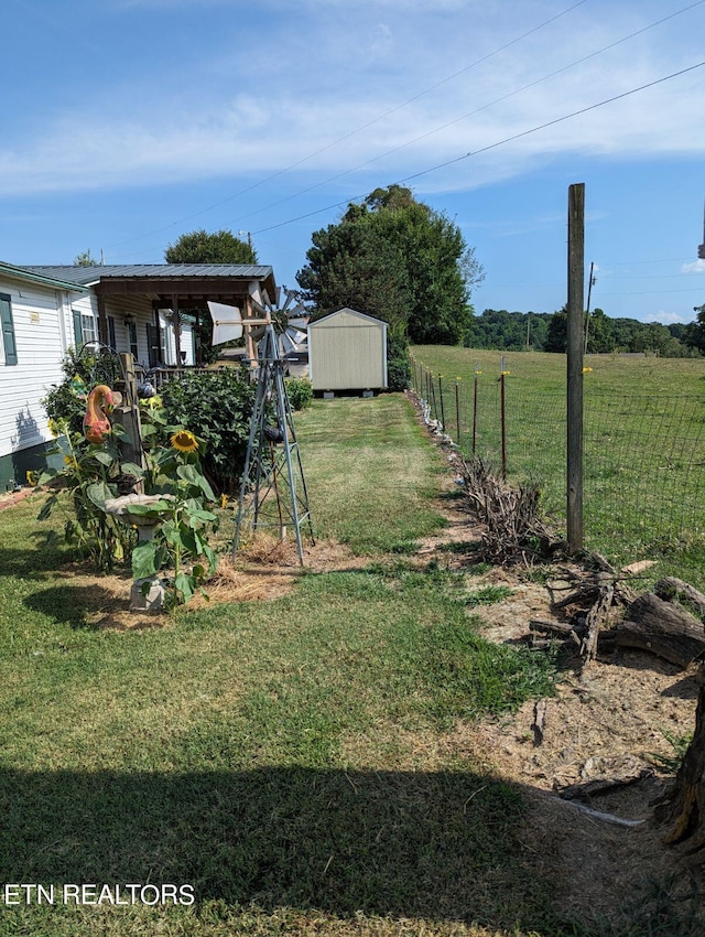 view of yard featuring a storage shed, fence, and an outbuilding