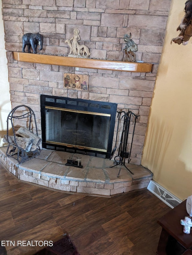 interior details featuring baseboards, a fireplace, visible vents, and wood finished floors