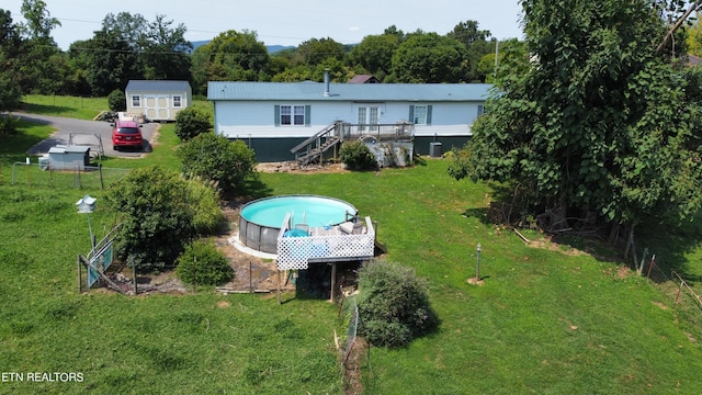 rear view of house featuring a lawn, stairway, a wooden deck, and fence