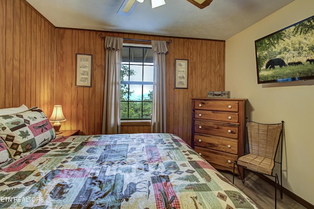 bedroom with ceiling fan and wood walls