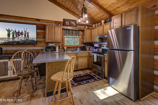 kitchen featuring appliances with stainless steel finishes, a kitchen bar, light hardwood / wood-style flooring, and lofted ceiling with beams