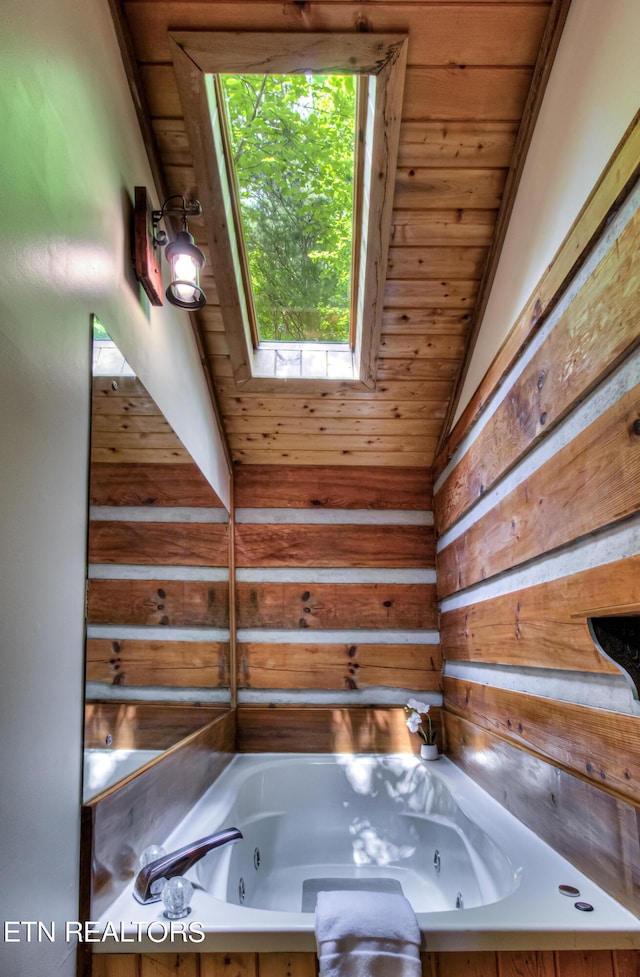 bathroom with vaulted ceiling with skylight, wood ceiling, and tiled tub