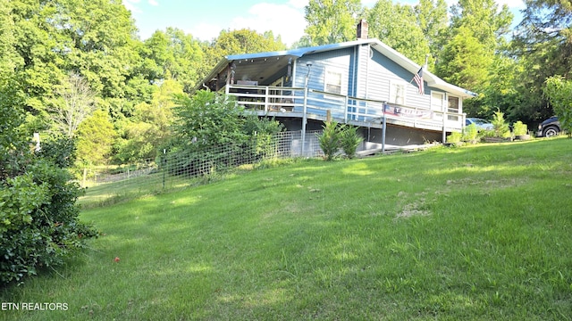 rear view of property featuring a wooden deck and a lawn