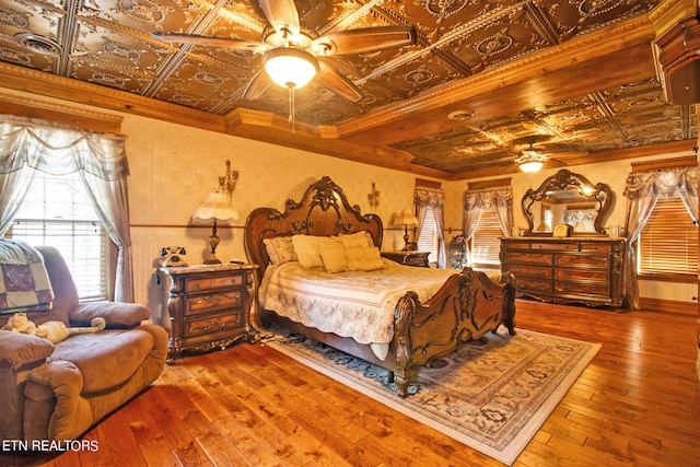 bedroom with hardwood / wood-style flooring, ornamental molding, coffered ceiling, and ceiling fan