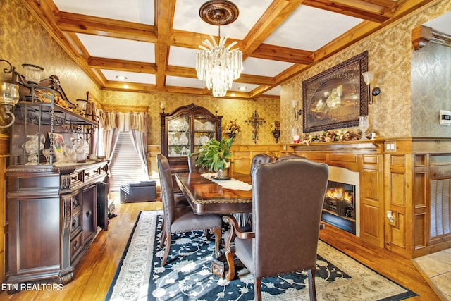 dining area featuring beamed ceiling, light hardwood / wood-style flooring, coffered ceiling, and a chandelier