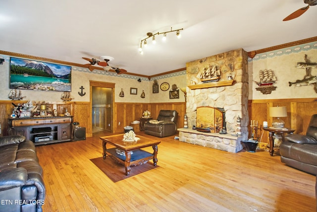 living room with a fireplace, rail lighting, ceiling fan, and hardwood / wood-style floors