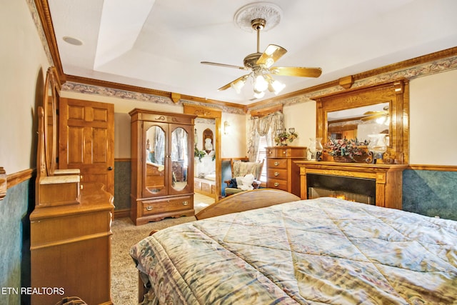 bedroom with light carpet, ceiling fan, and a raised ceiling