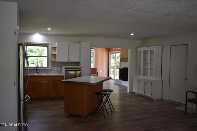 kitchen featuring a kitchen island, white cabinetry, plenty of natural light, sink, and fridge