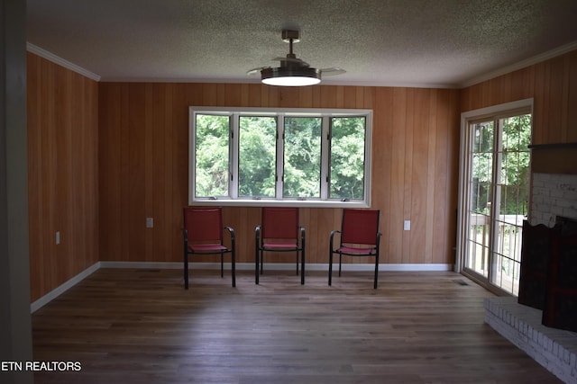 dining room with wood-type flooring, a wealth of natural light, crown molding, and a fireplace