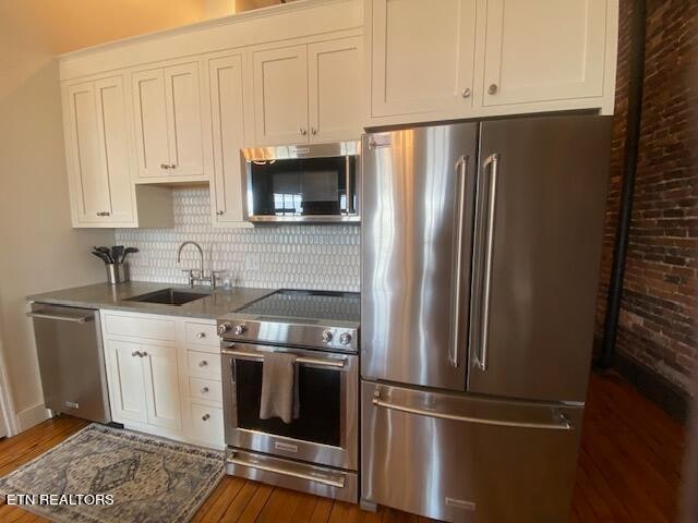 kitchen with white cabinets, sink, stainless steel appliances, and dark wood-type flooring