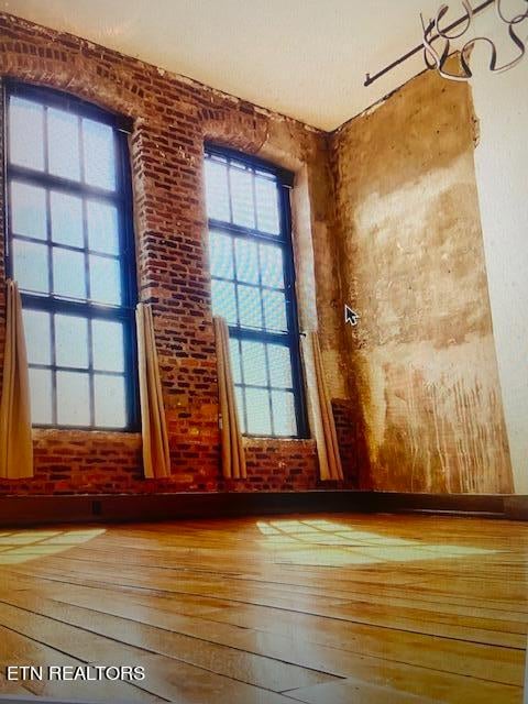 spare room featuring hardwood / wood-style floors and brick wall