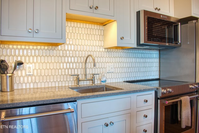 kitchen with light stone counters, sink, white cabinets, and stainless steel appliances