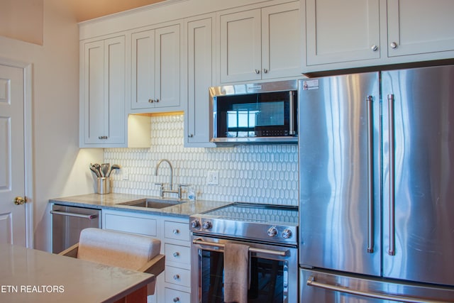 kitchen featuring light stone countertops, appliances with stainless steel finishes, white cabinetry, and sink