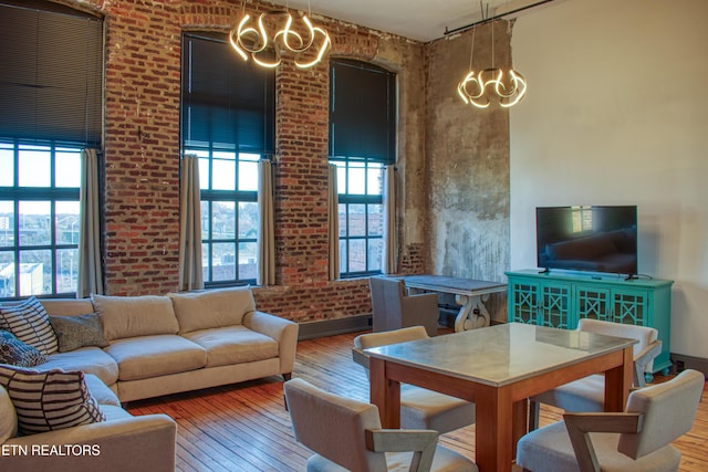 living room with brick wall, a notable chandelier, and hardwood / wood-style flooring