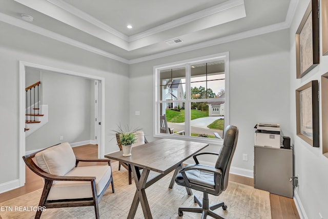 office with ornamental molding, light hardwood / wood-style flooring, and a raised ceiling