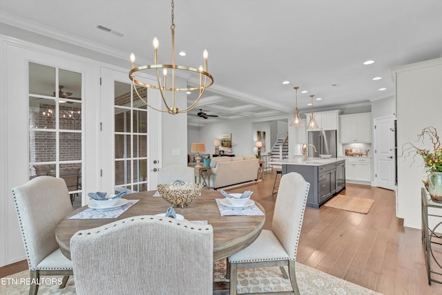 dining room featuring light hardwood / wood-style flooring, beam ceiling, ceiling fan with notable chandelier, and crown molding