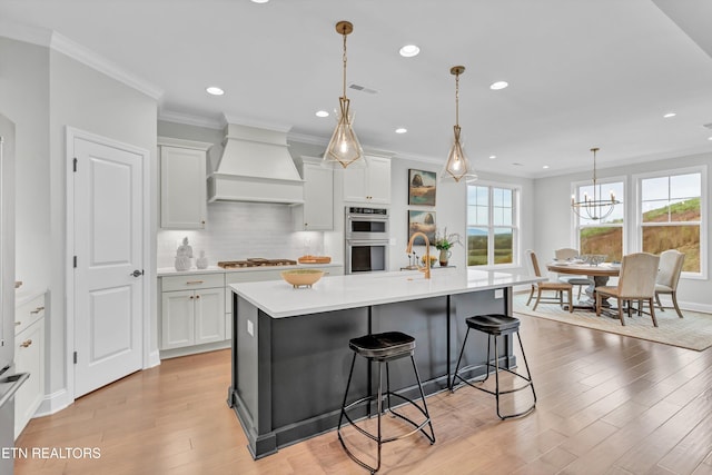 kitchen featuring a spacious island, premium range hood, white cabinets, and light wood-type flooring