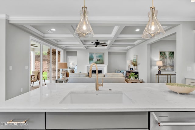 kitchen with light stone countertops, sink, an island with sink, and pendant lighting