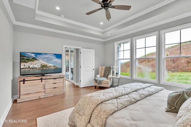 bedroom with ceiling fan, access to outside, hardwood / wood-style flooring, a tray ceiling, and ornamental molding