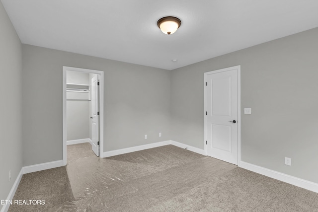 unfurnished bedroom featuring a closet, carpet floors, and a walk in closet