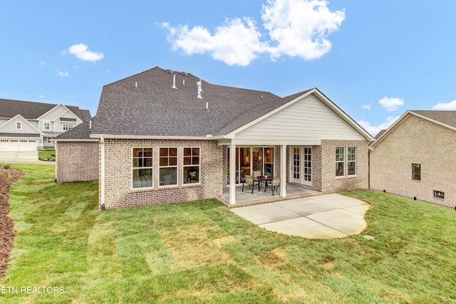 rear view of property with a patio, a lawn, and a garage