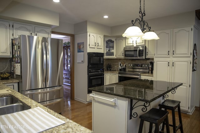 kitchen featuring stone counters, backsplash, stainless steel appliances, dark hardwood / wood-style floors, and a kitchen island