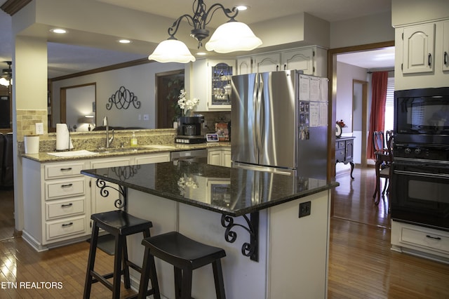 kitchen featuring decorative light fixtures, kitchen peninsula, a kitchen bar, and black appliances