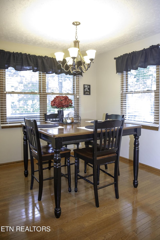 dining area with plenty of natural light, an inviting chandelier, a textured ceiling, and dark hardwood / wood-style flooring