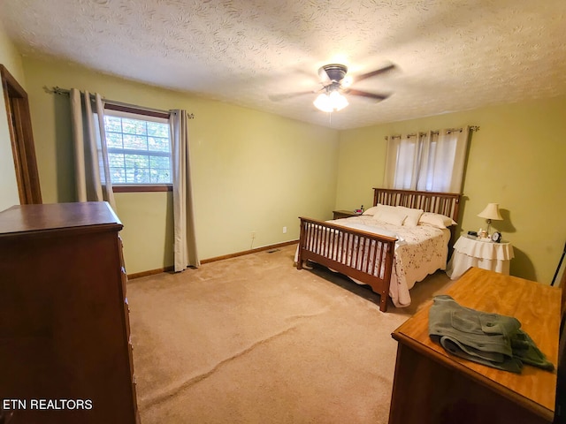 bedroom featuring light carpet, a textured ceiling, and ceiling fan