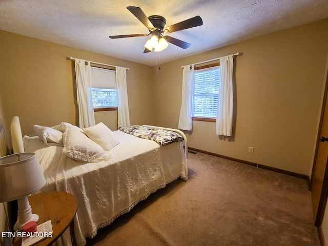 carpeted bedroom with multiple windows, a textured ceiling, and ceiling fan