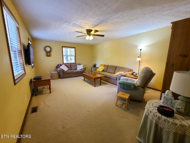 living room featuring carpet flooring, ceiling fan, and a textured ceiling