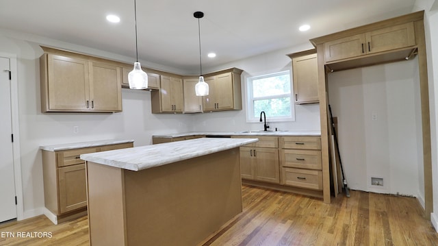 kitchen with pendant lighting, a center island, light brown cabinets, sink, and light wood-type flooring