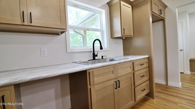 kitchen featuring light brown cabinetry, light stone countertops, sink, and light hardwood / wood-style flooring